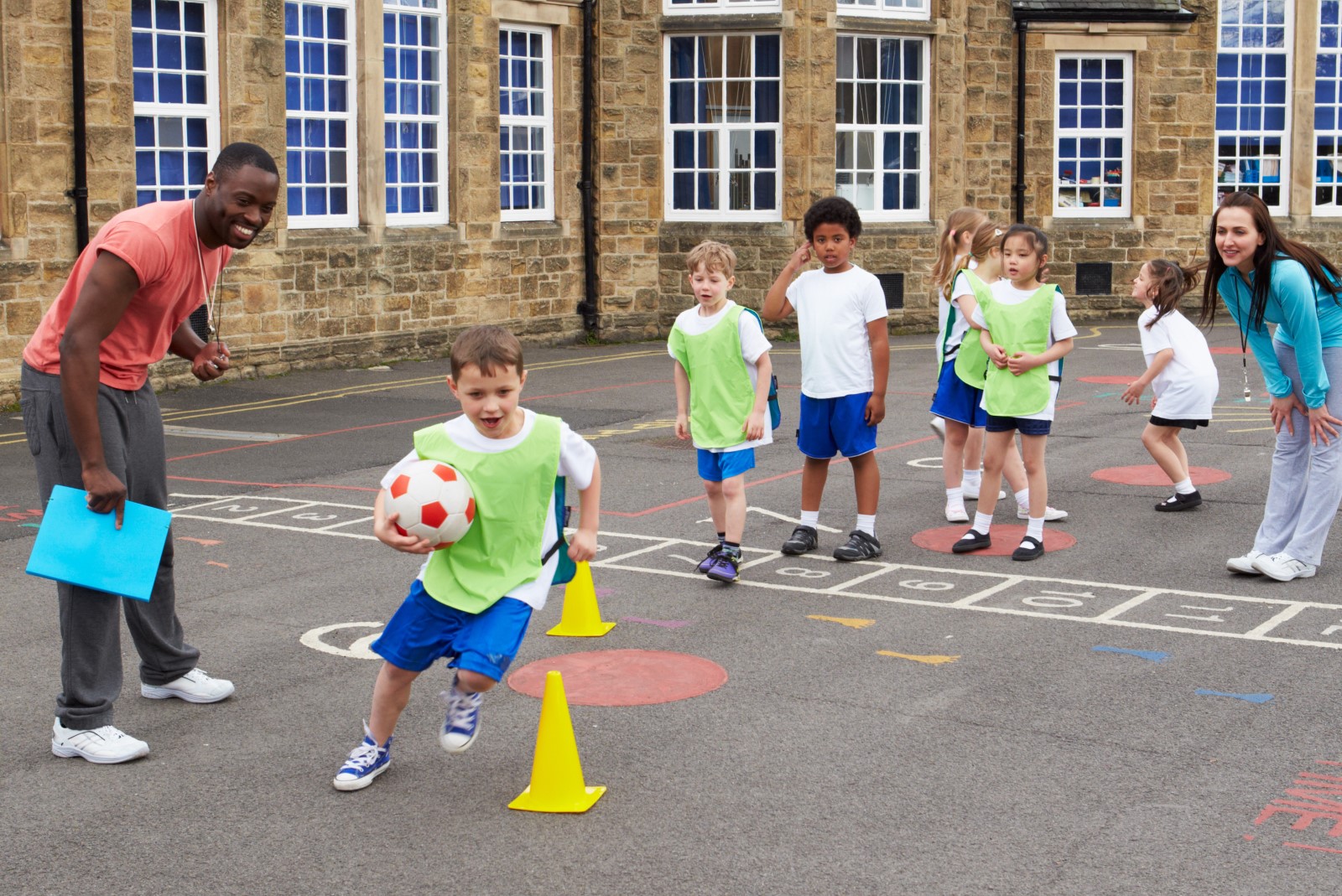 Children playing in a school playground with teachers.jpg