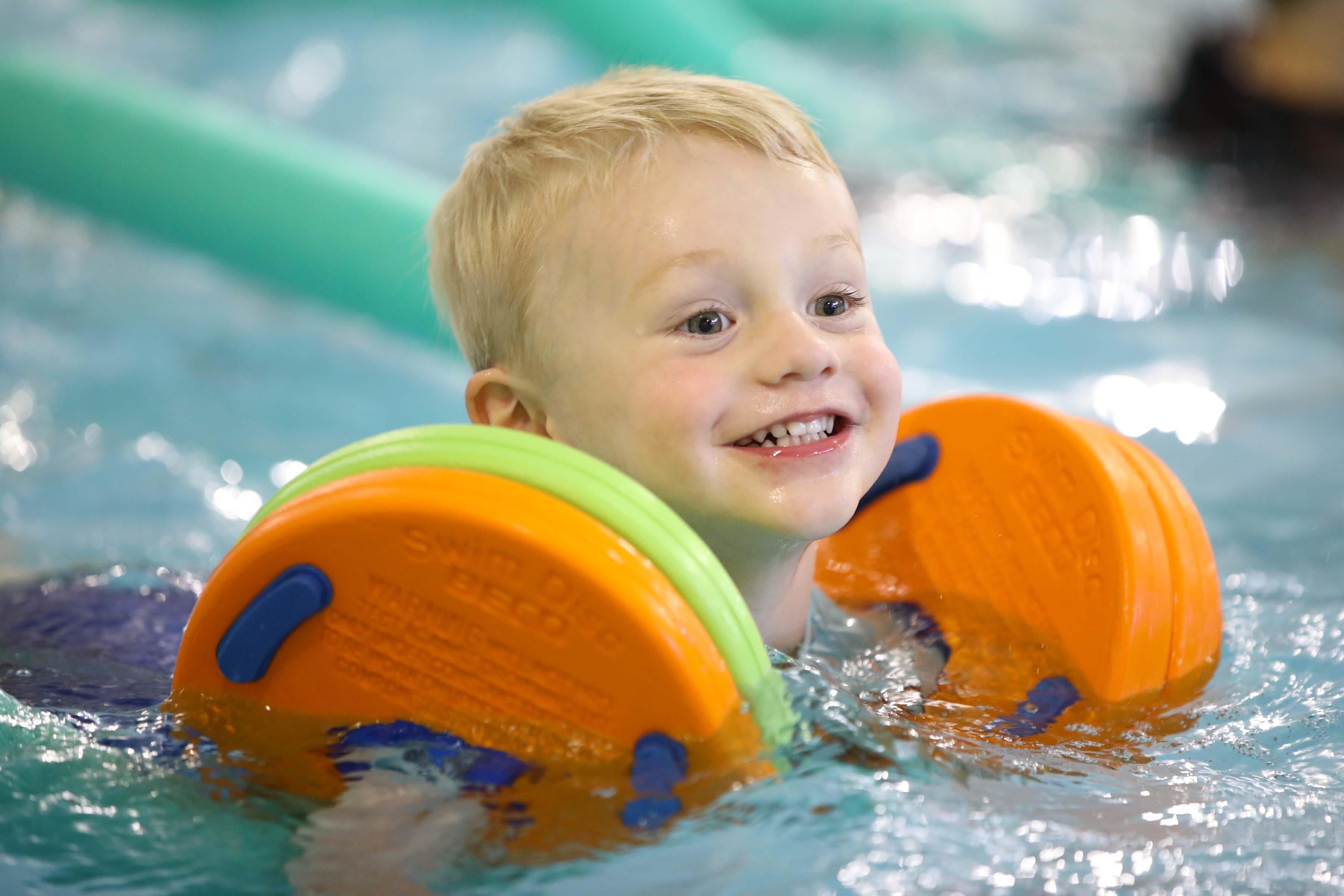 Little boy with orange arm floats in a pool